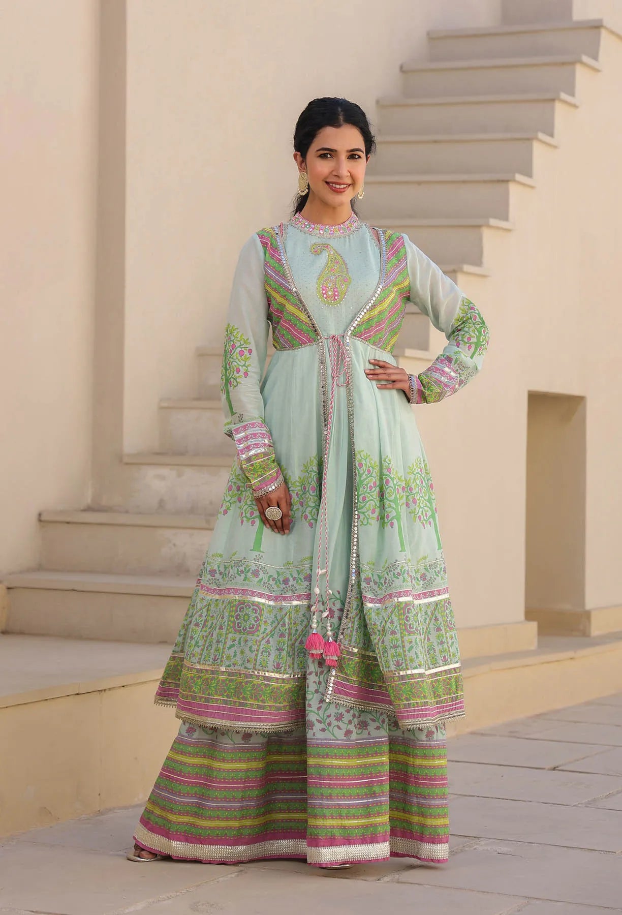 Woman in a traditional outfit standing on steps with a neutral background