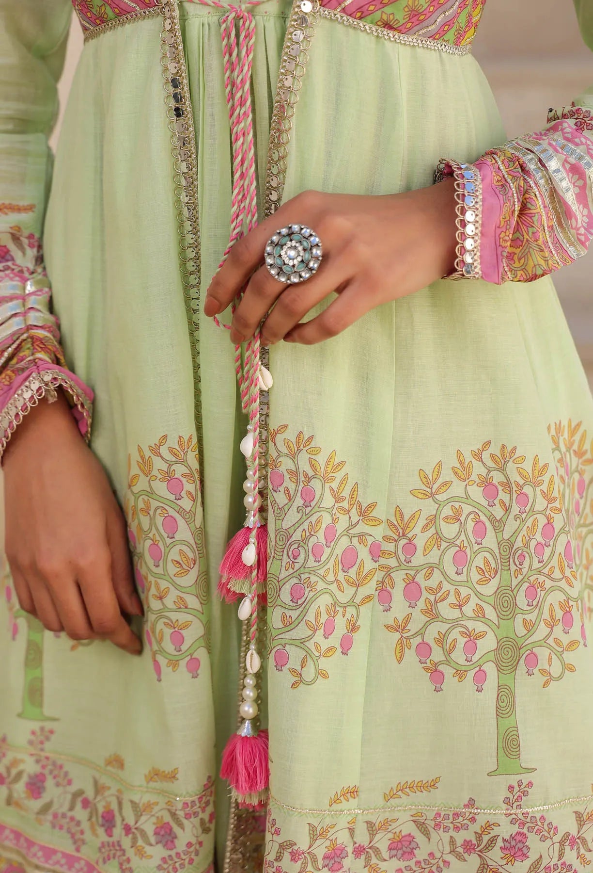 Light green traditional outfit with floral patterns and pink accents, worn by a person.