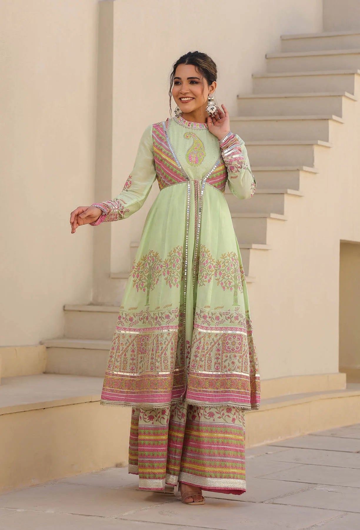 Woman in a traditional outfit standing on steps with a neutral background