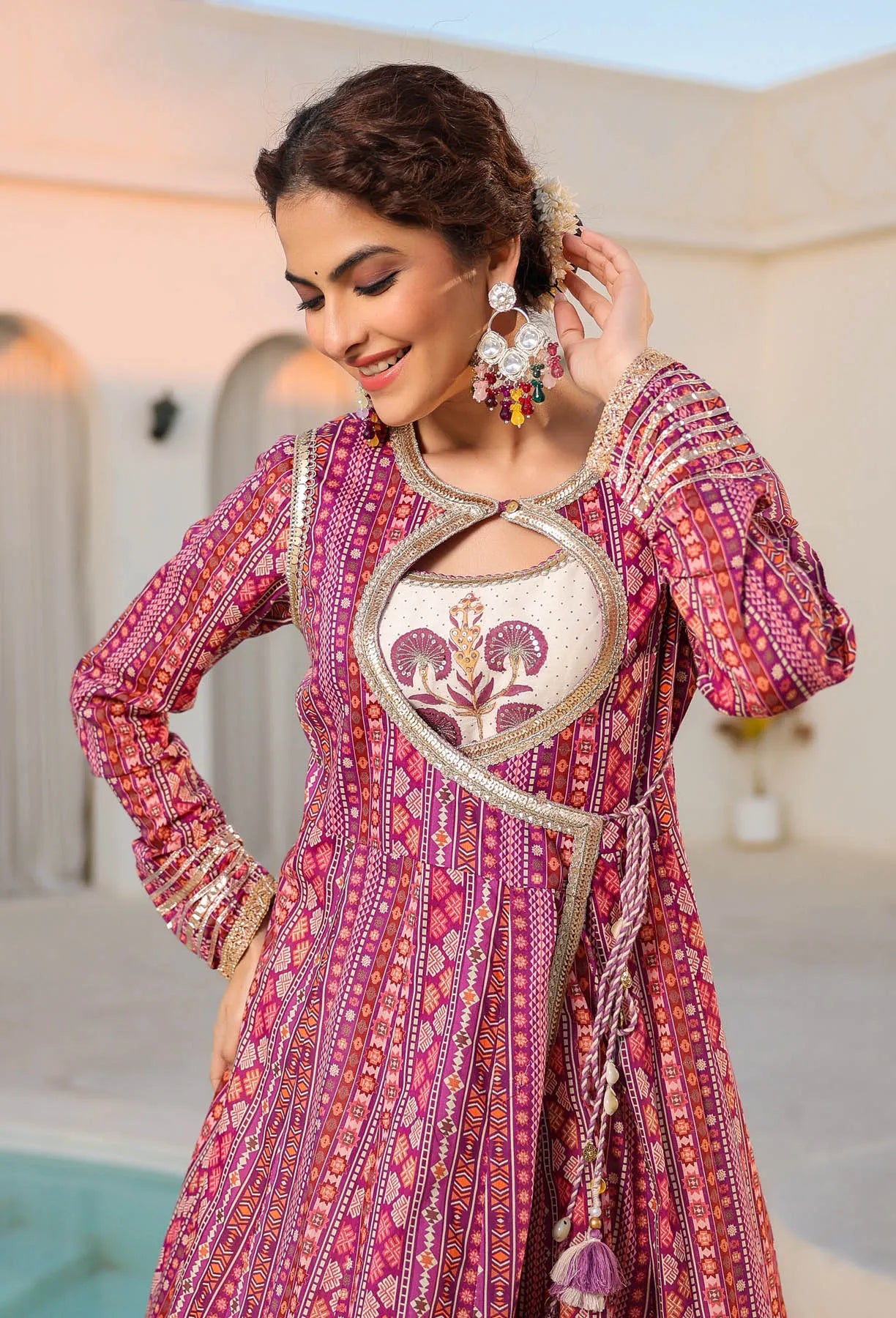 Woman wearing a traditional pink and red embroidered outfit with intricate patterns.