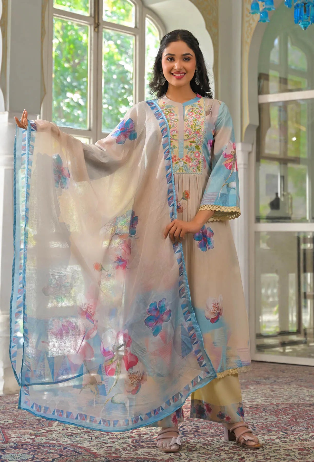 Woman in traditional outfit with floral dupatta in a well-lit room