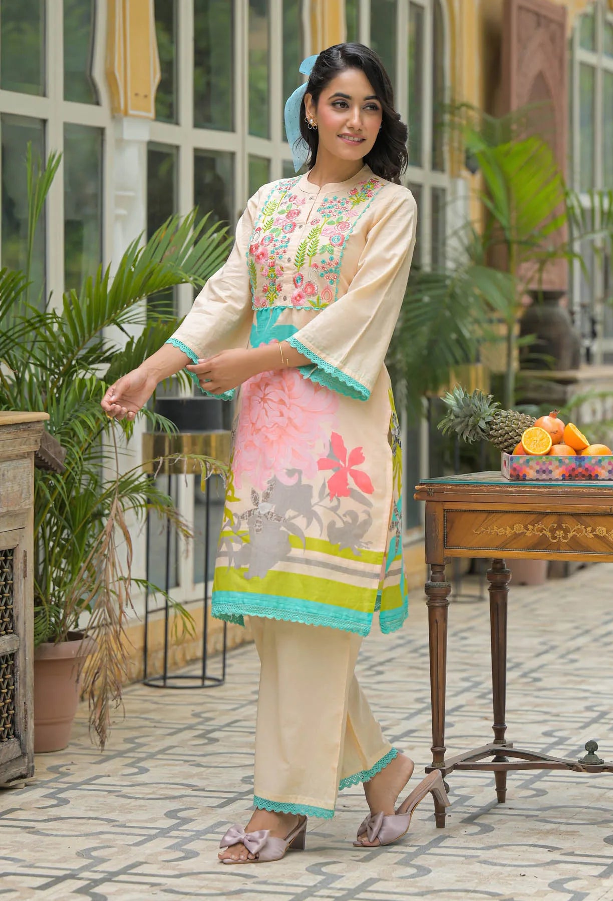 Woman in a floral dress standing outdoors with plants and a table in the background