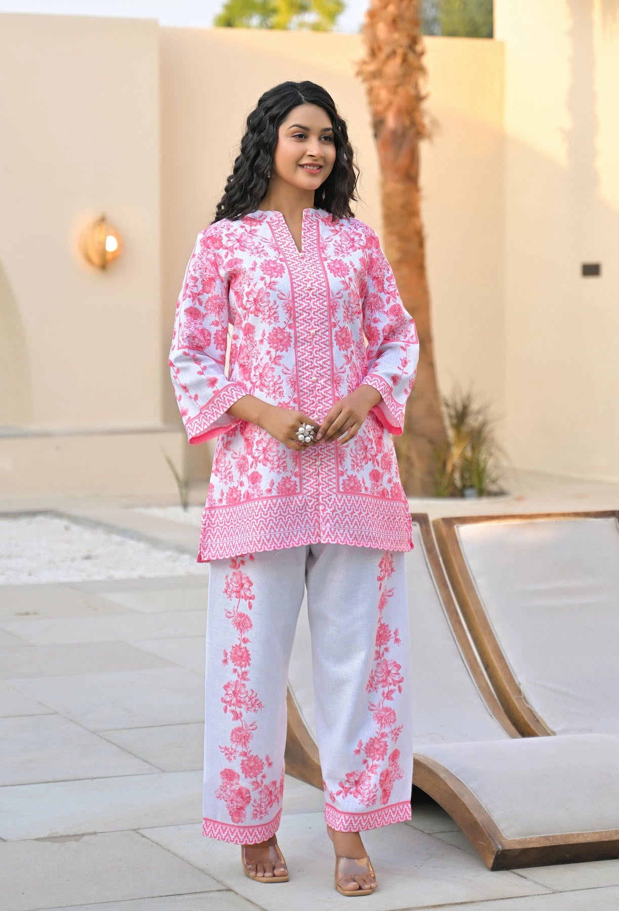 Woman wearing a pink and white floral outfit standing outdoors.