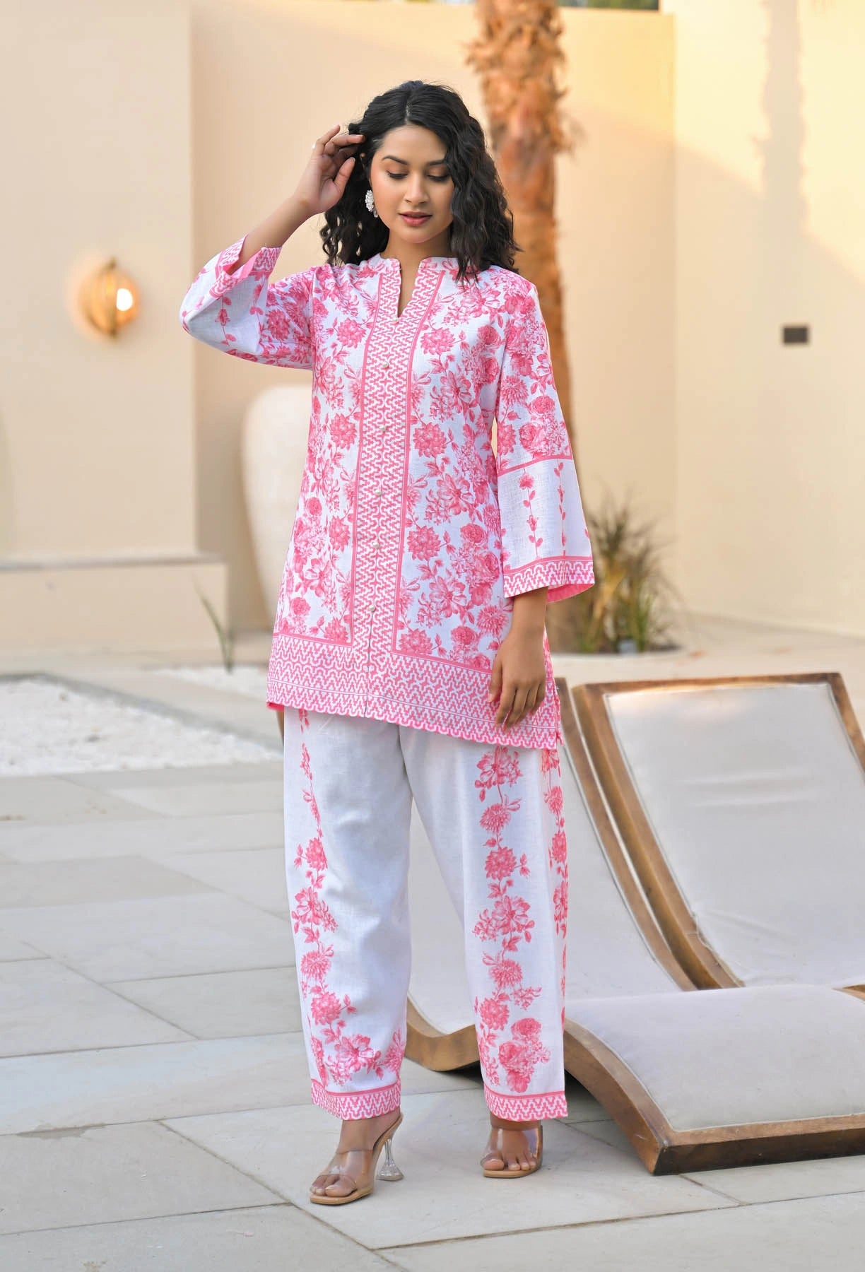 Woman wearing a pink and white floral outfit standing outdoors.