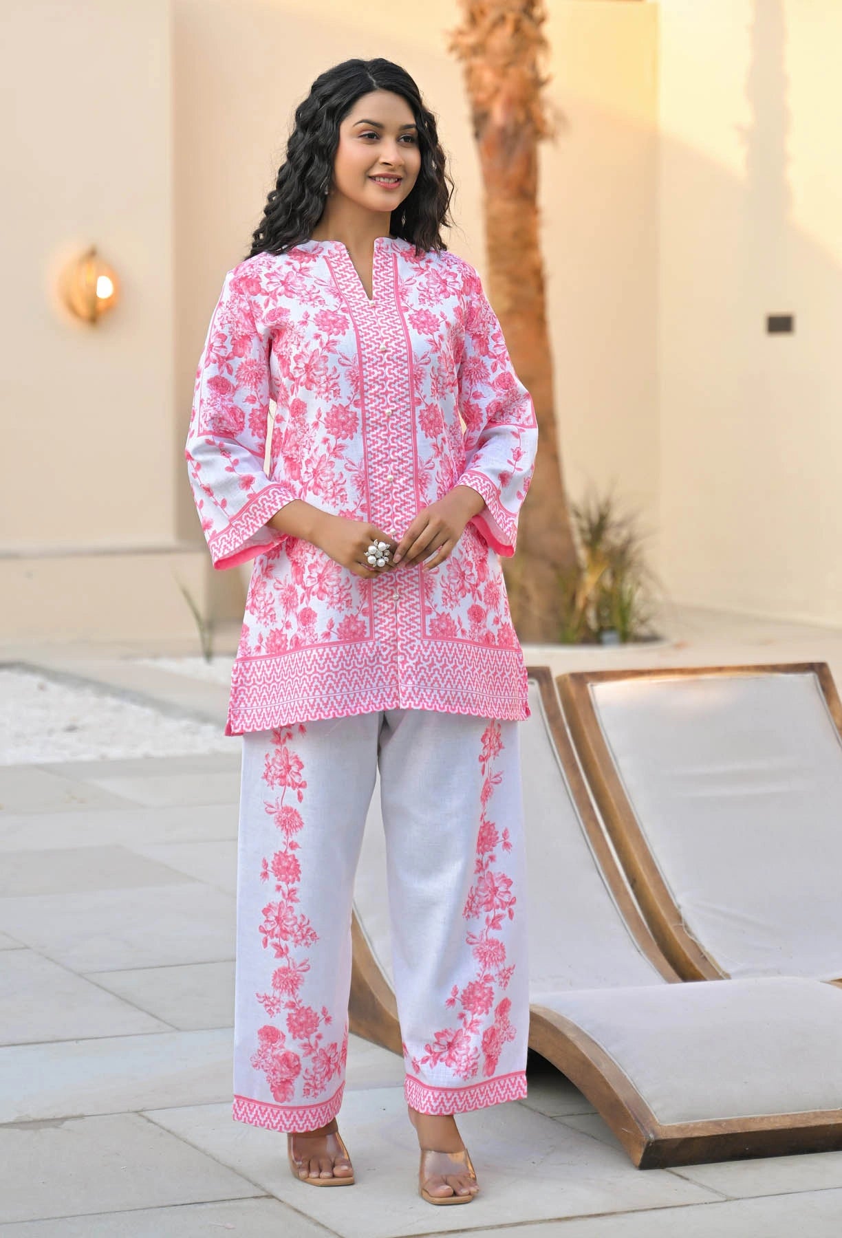 Woman wearing a pink and white embroidered outfit standing outdoors.