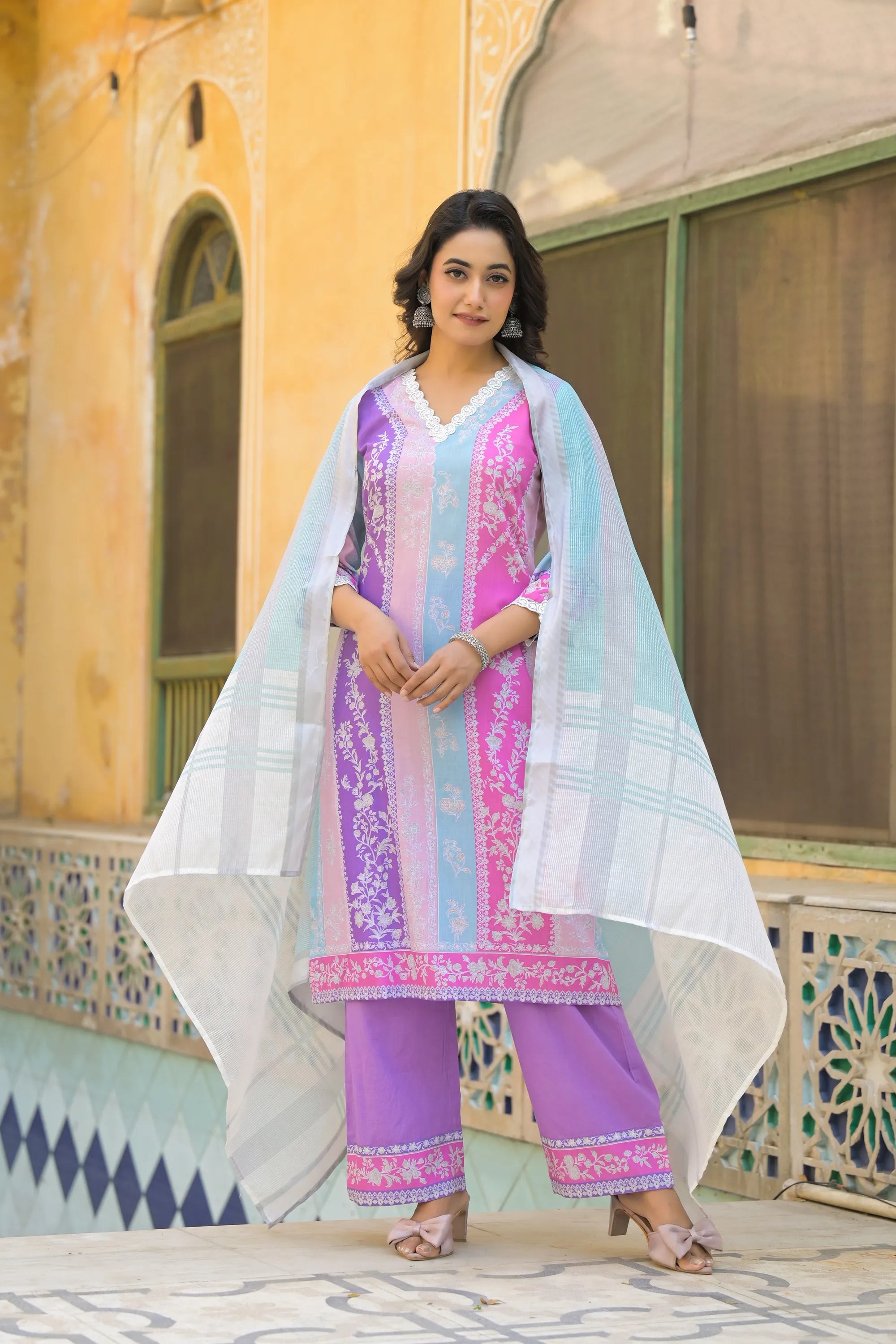 Woman in a traditional outfit standing in front of a decorative building.