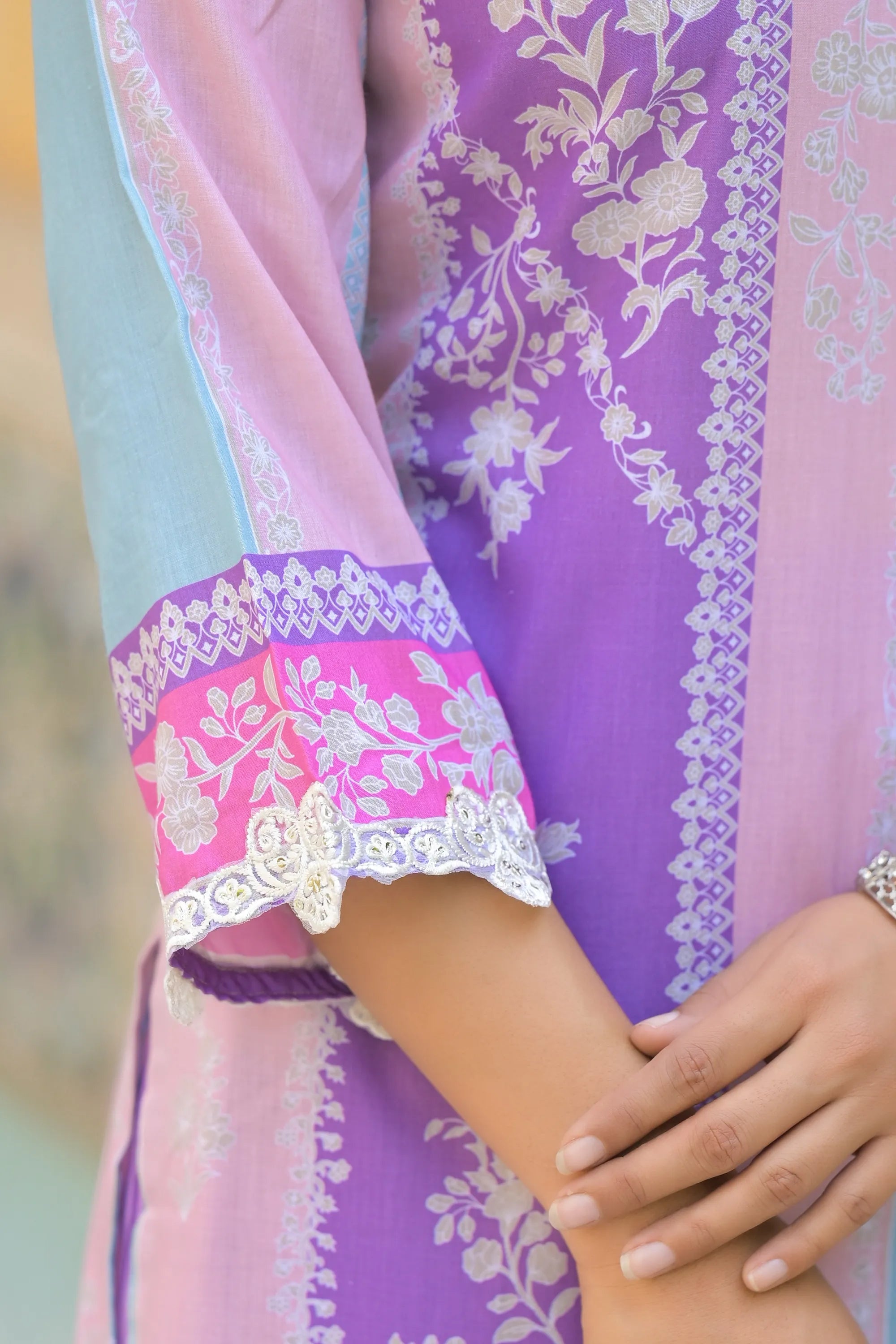 Close-up of a person wearing a purple and pink traditional outfit with floral patterns.