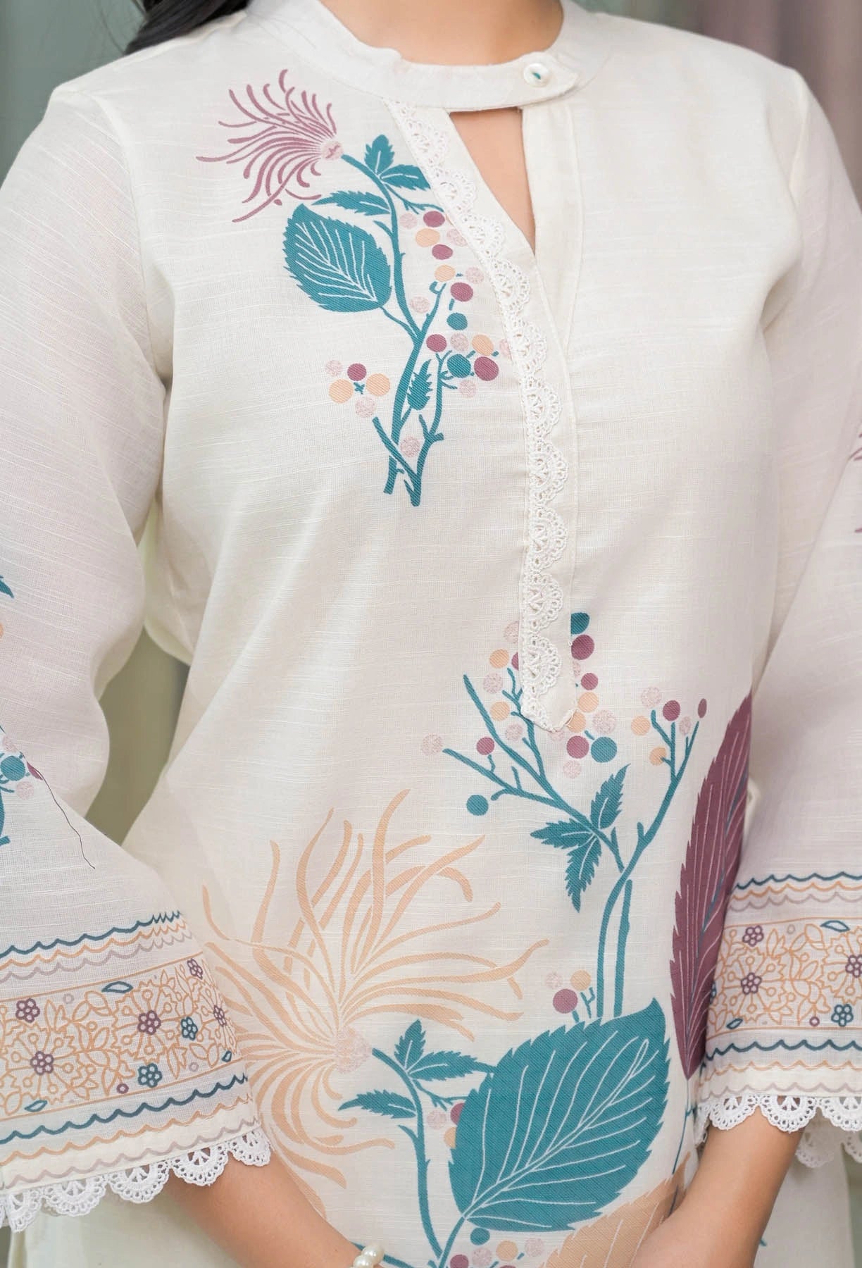White embroidered garment with colorful floral patterns on a neutral background