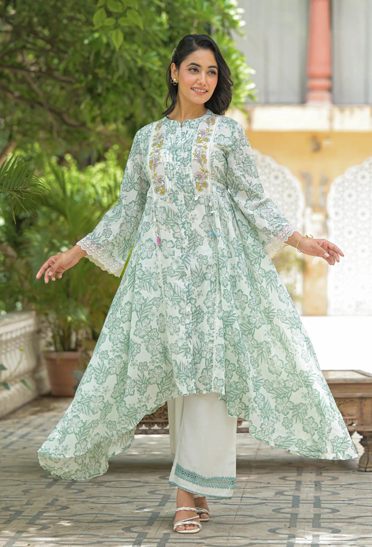Woman in a light green floral dress standing outdoors with greenery in the background