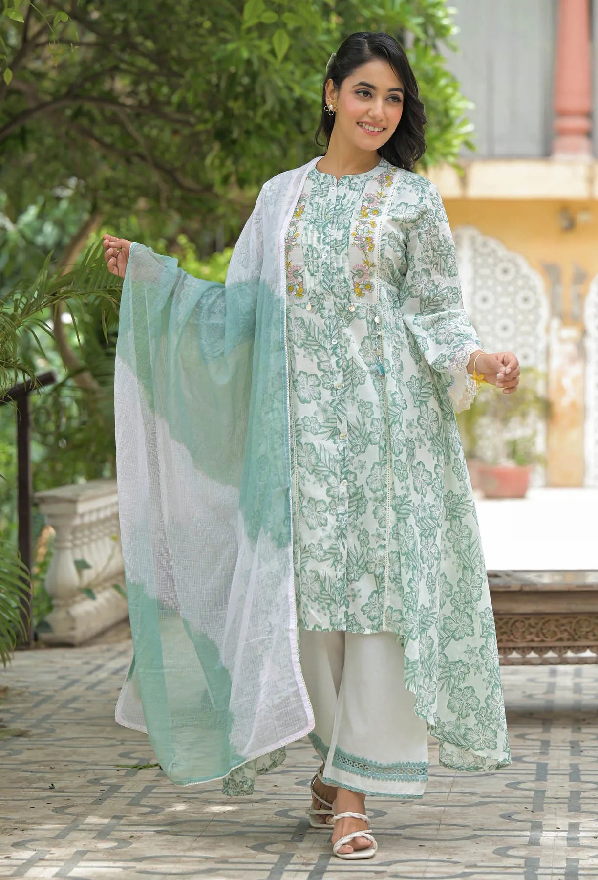Woman in a light green and white traditional outfit with a matching dupatta, standing outdoors.