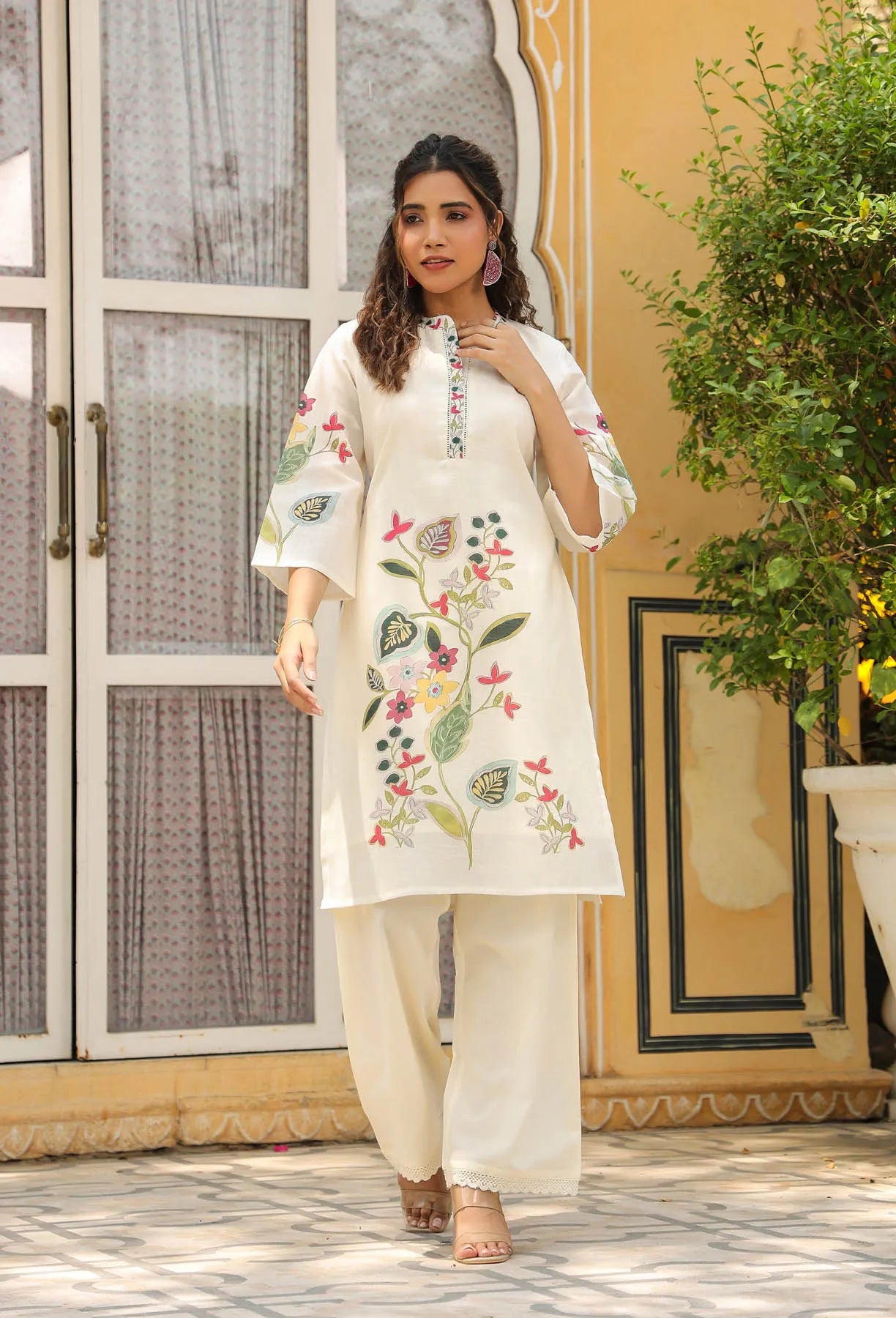 Woman wearing a white embroidered kurta with palazzo pants standing outdoors.