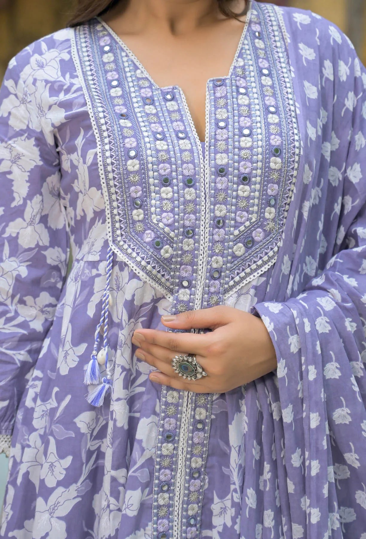 Close-up of a person wearing a purple embroidered dress with floral patterns.