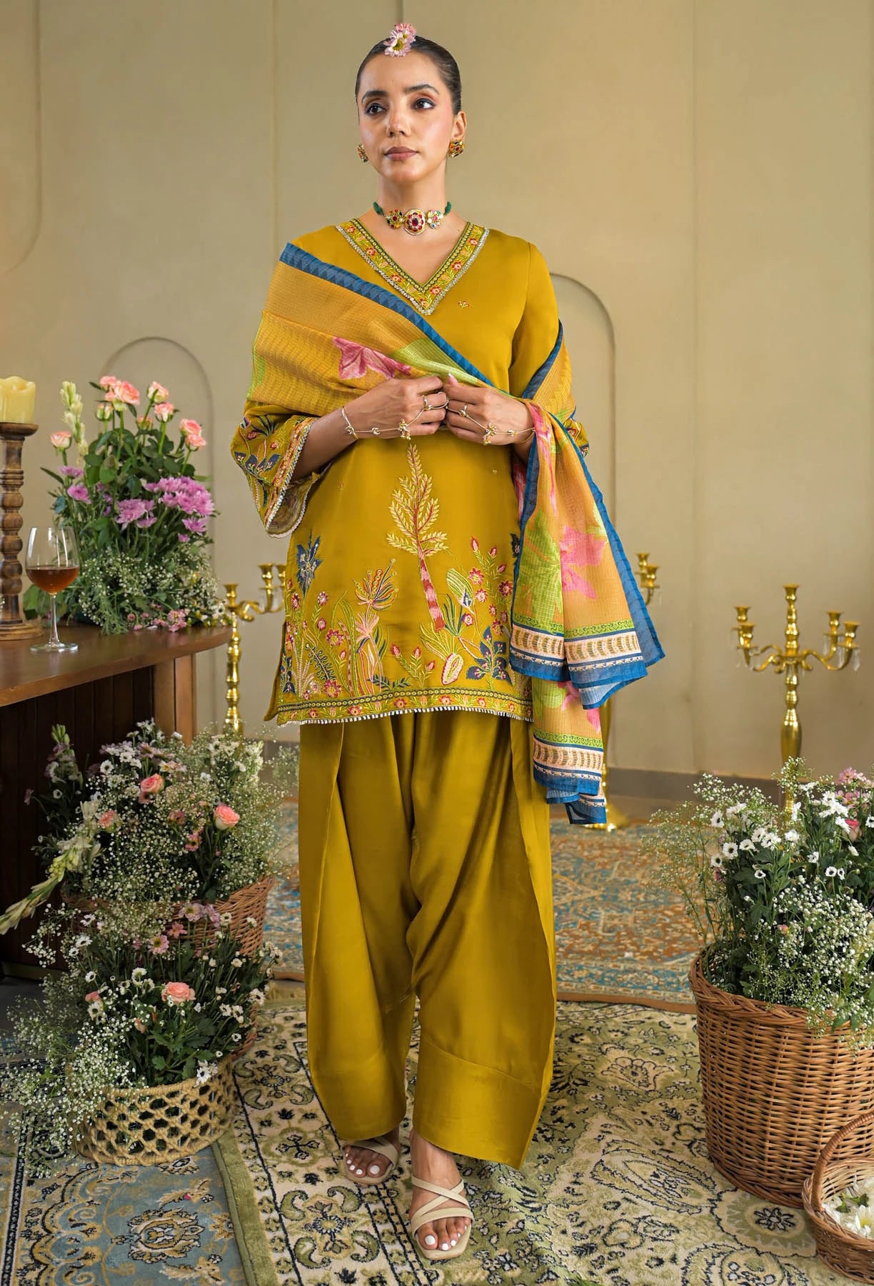 Woman in a traditional outfit with a colorful dupatta in an elegant room.
