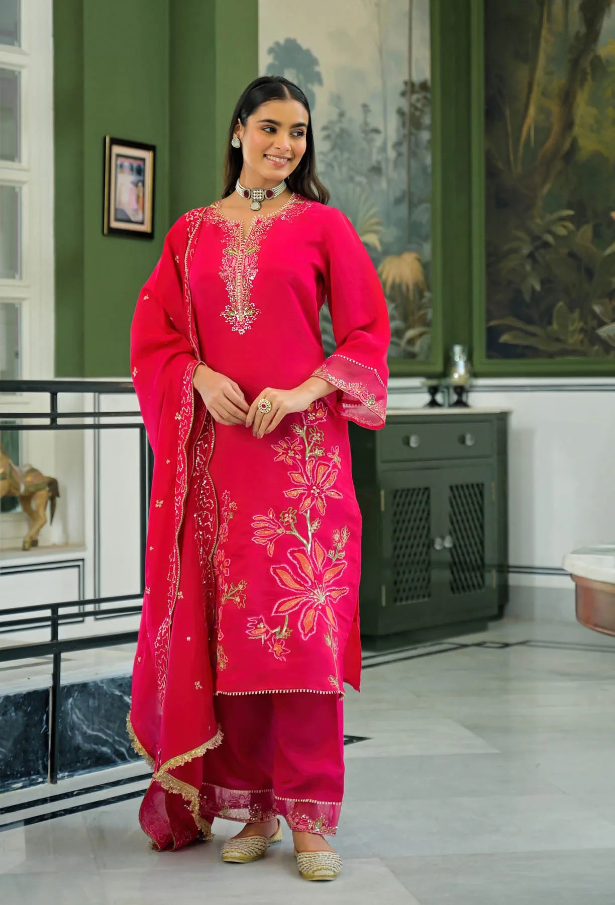Woman wearing a red embroidered traditional outfit in an indoor setting.