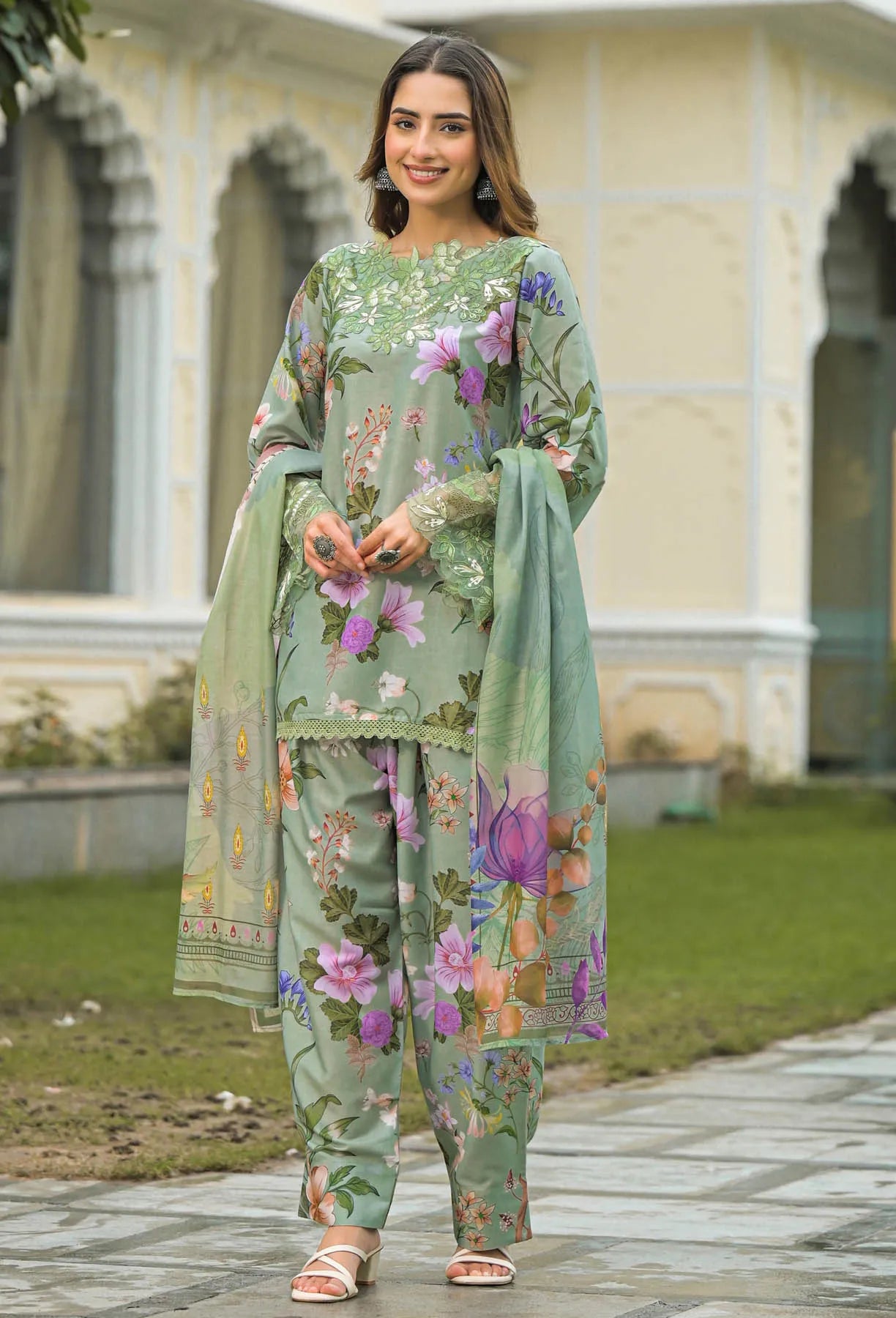 Woman wearing a green floral outfit standing outdoors with a building in the background