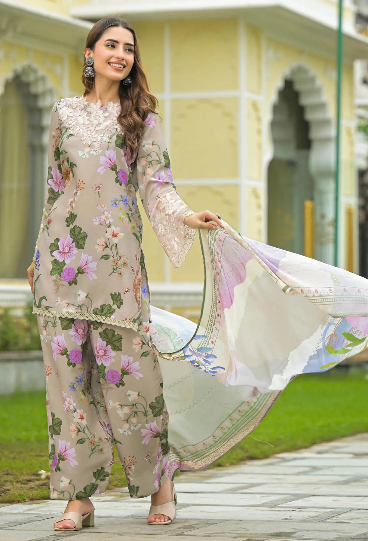 Woman in a floral outfit standing outdoors with a building in the background