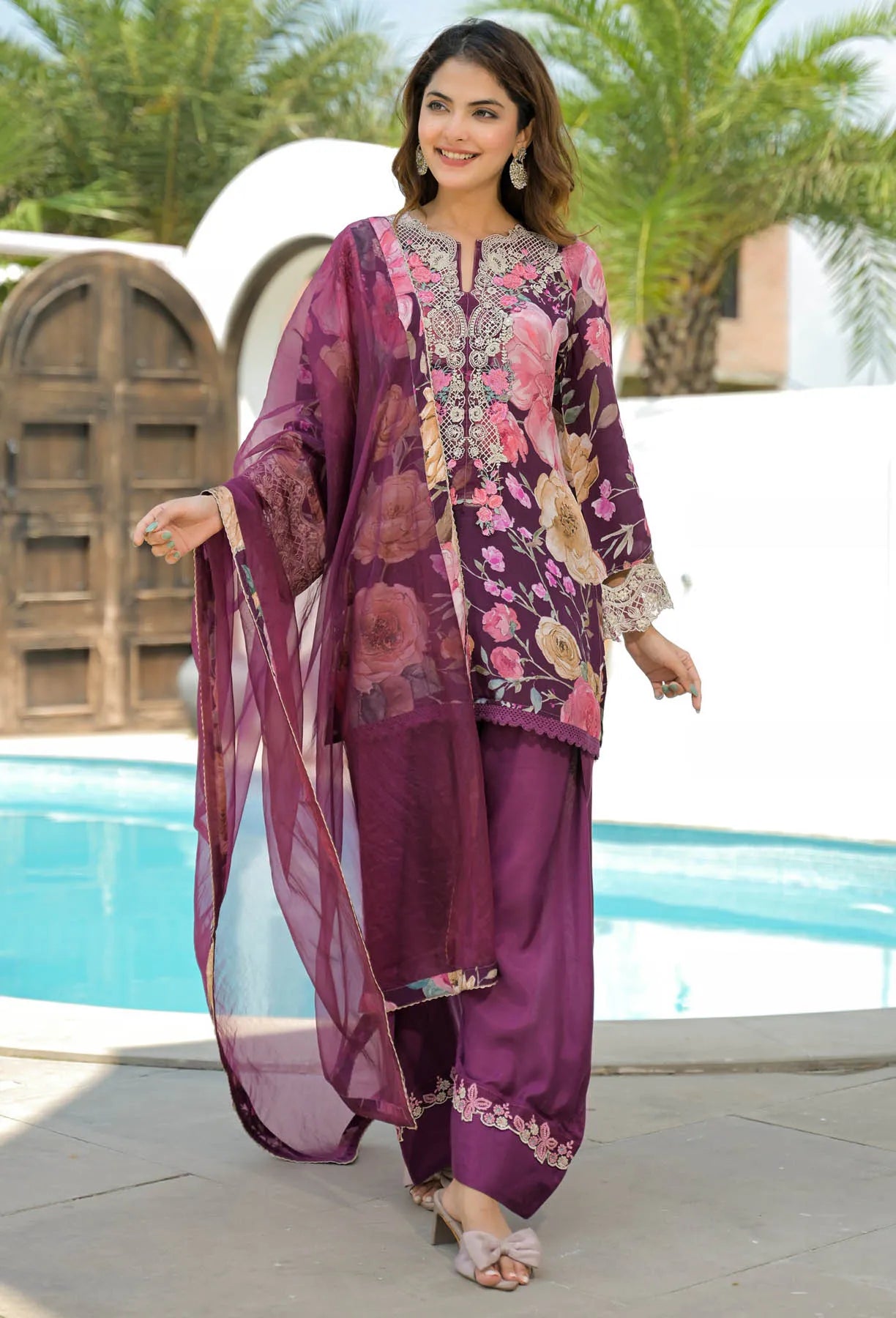 Woman in a traditional outfit by a poolside with greenery in the background