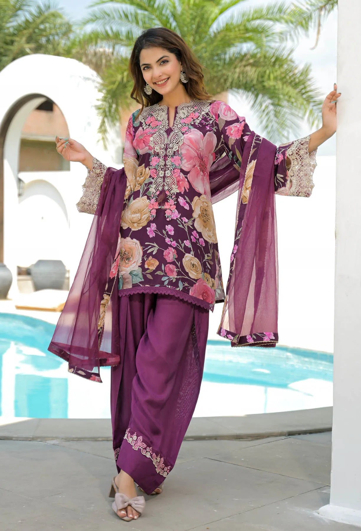 Woman in a floral and purple outfit by a poolside