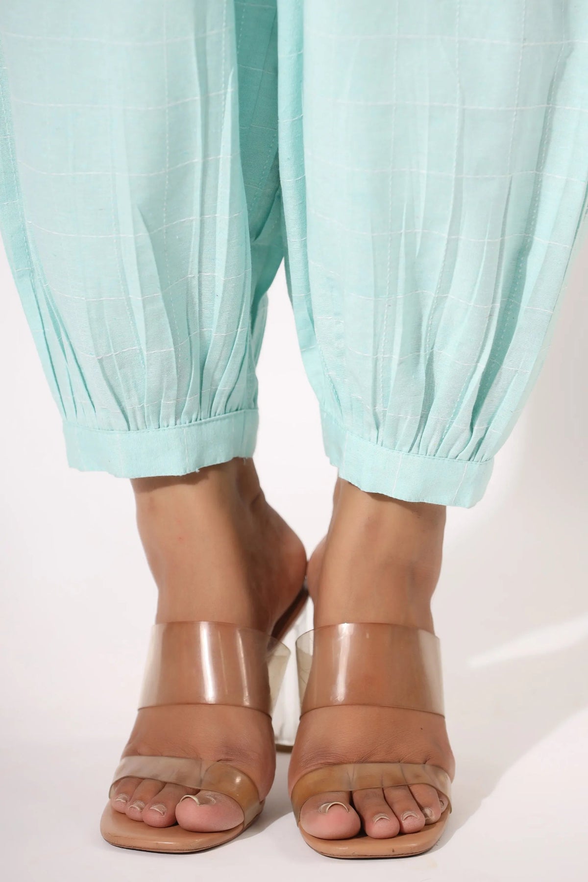 Light blue pants worn with brown open-toe sandals on a white background