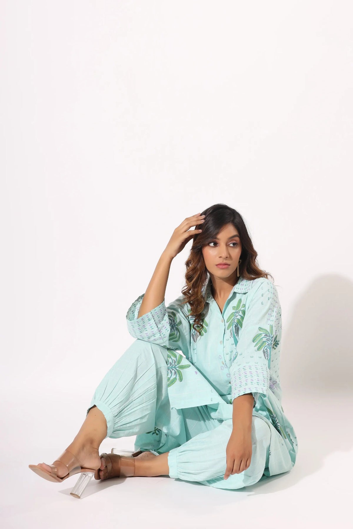 Woman wearing a light blue outfit with floral patterns on a white background