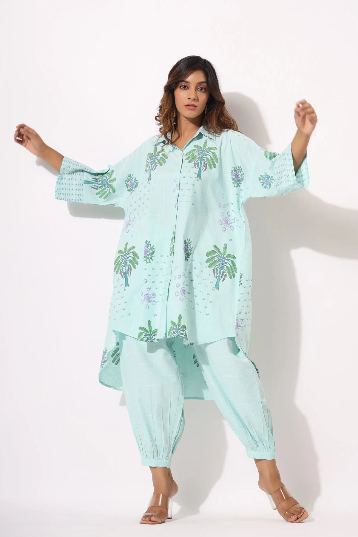 Woman wearing a light blue traditional outfit with floral patterns on a white background