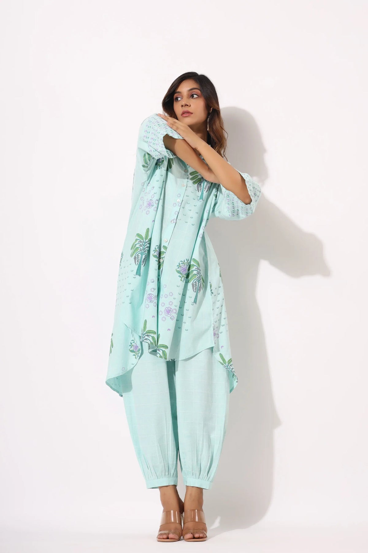 Woman wearing a light blue outfit with floral patterns on a white background