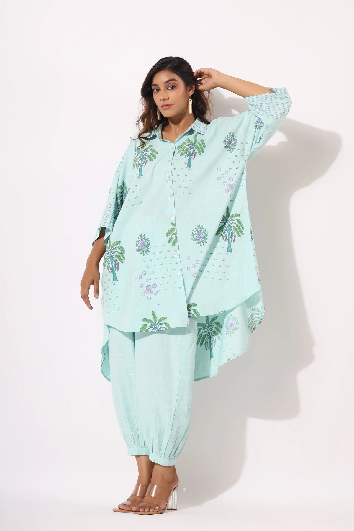 Woman wearing a light blue traditional outfit with floral patterns on a white background