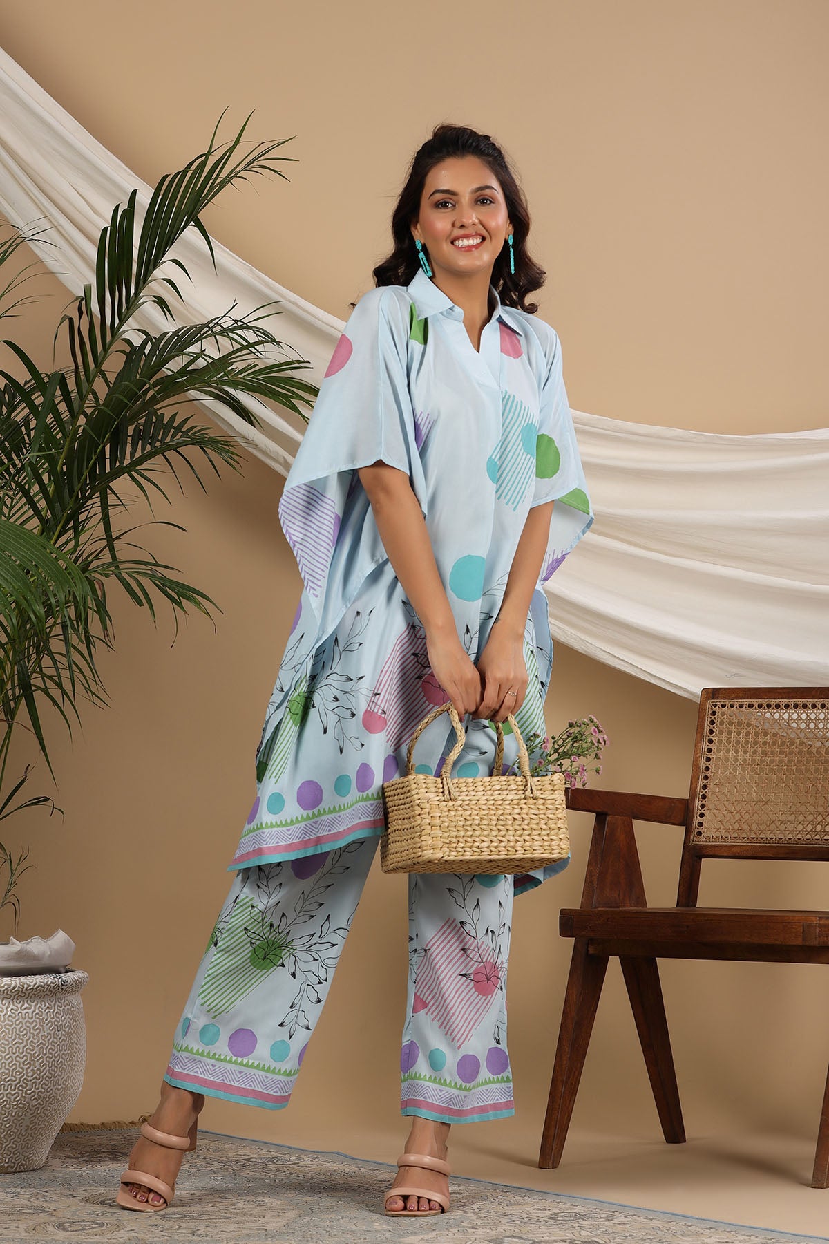 Woman in a light blue patterned outfit holding a woven basket indoors.