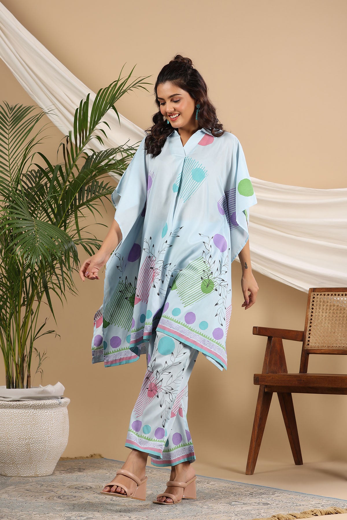 Woman wearing a light blue floral dress with a patterned shawl in a home setting.