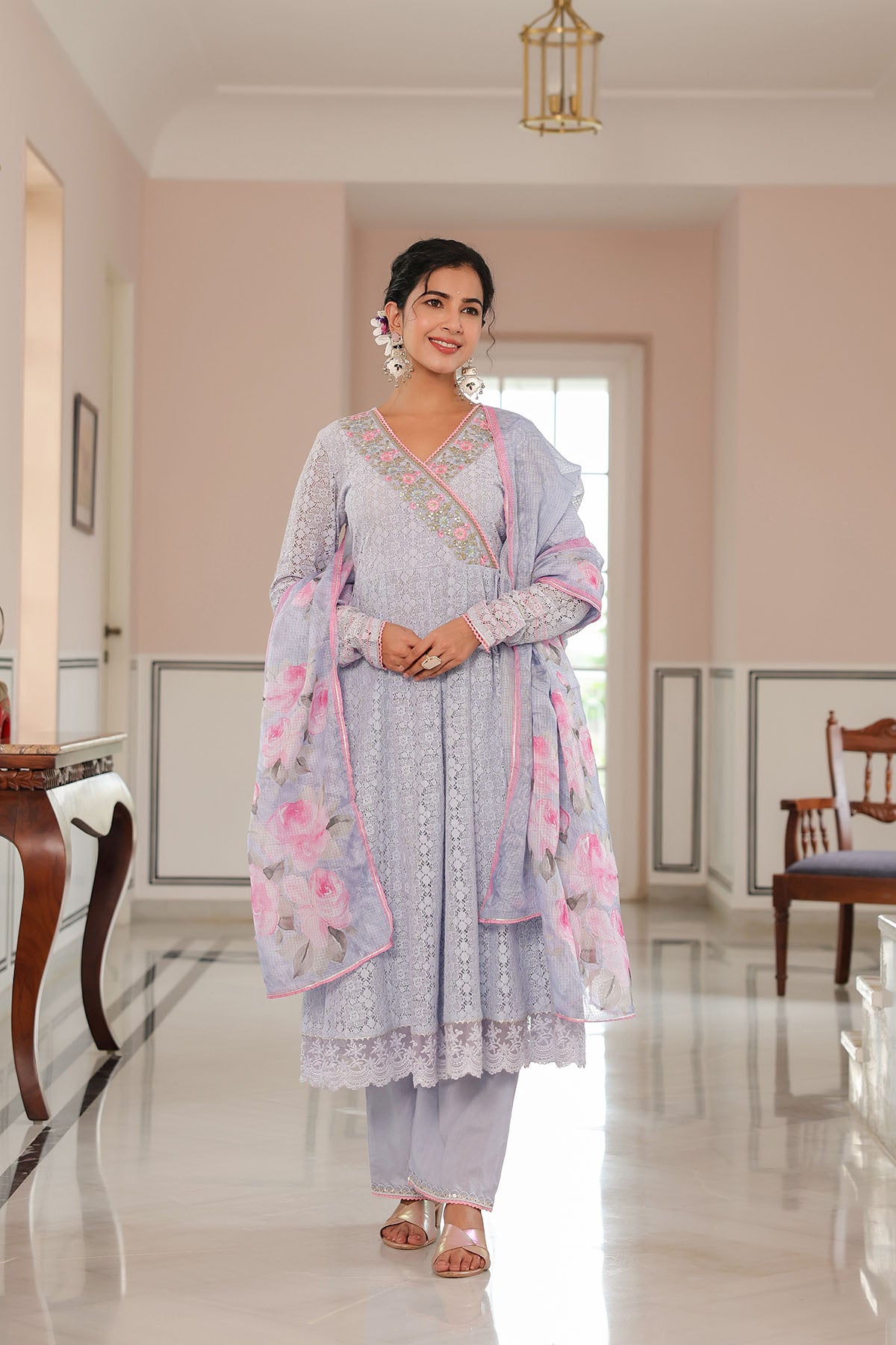 Woman in a light blue traditional outfit with pink accents standing in a well-lit room.