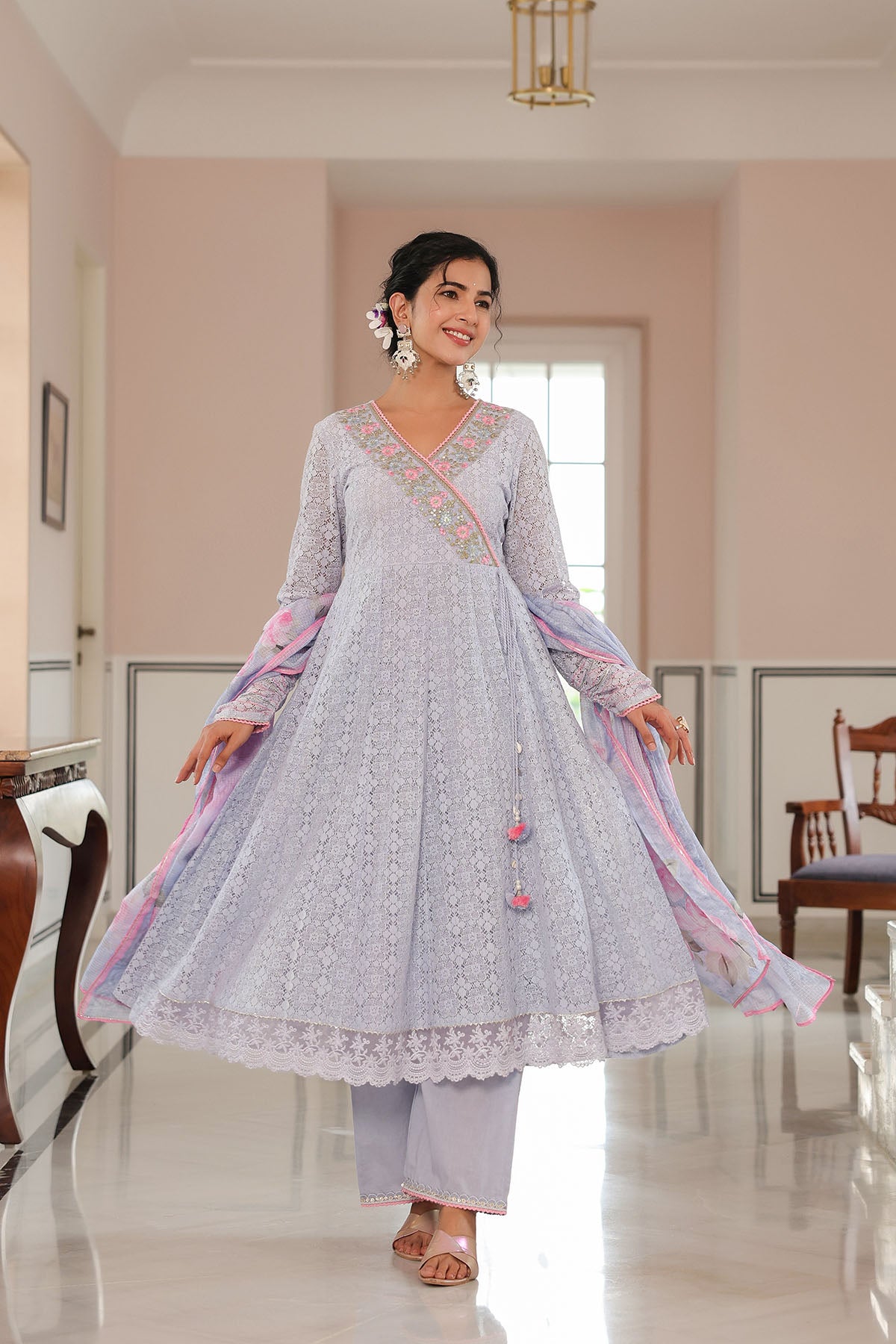 Woman in a light blue traditional outfit with pink accents in a well-lit room.