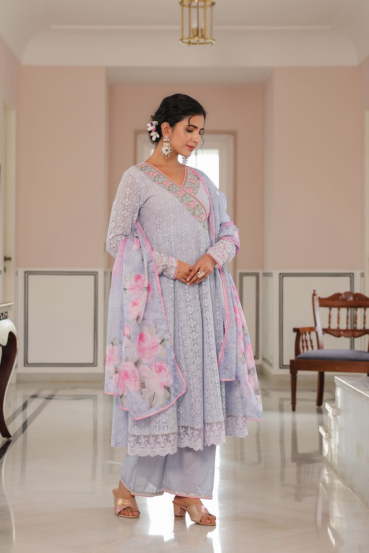 Woman in a light blue traditional outfit with floral patterns in a room.