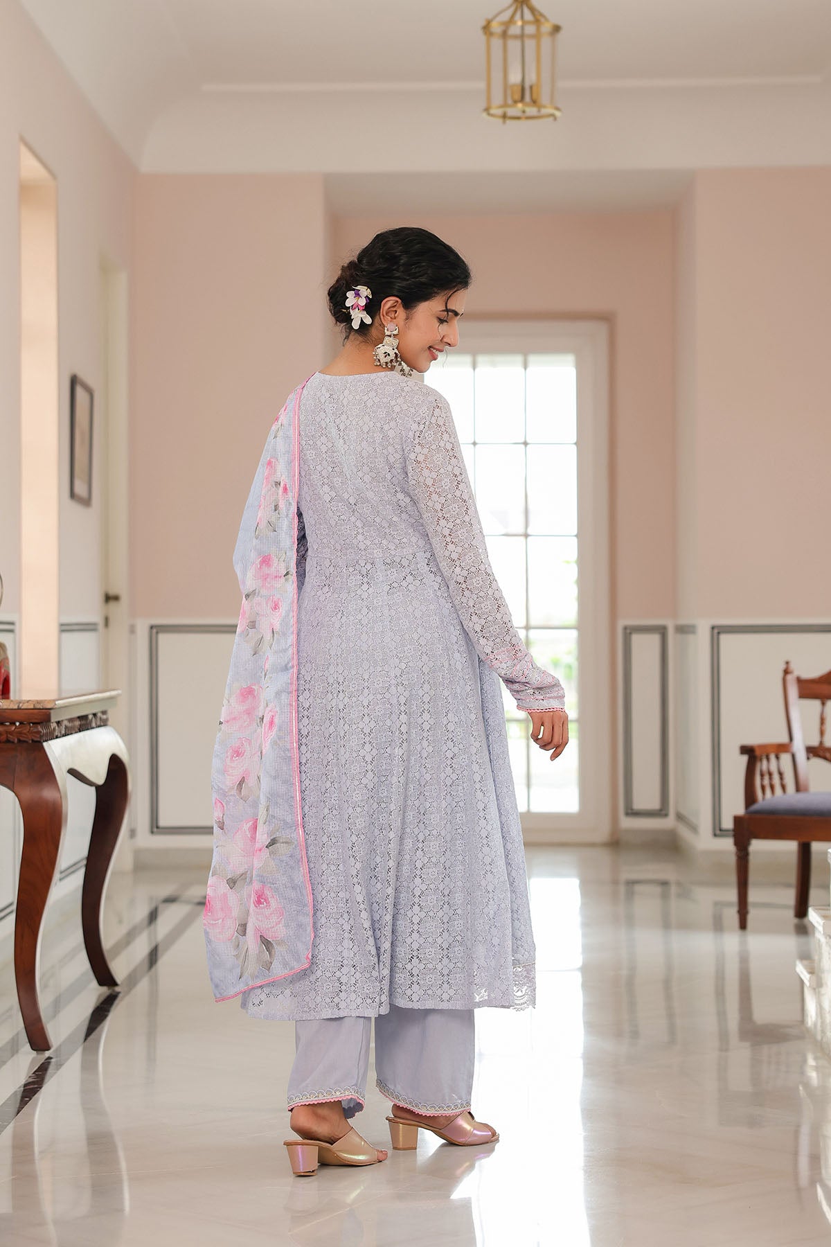 Woman in a light gray traditional outfit with a pink dupatta in a well-lit room.