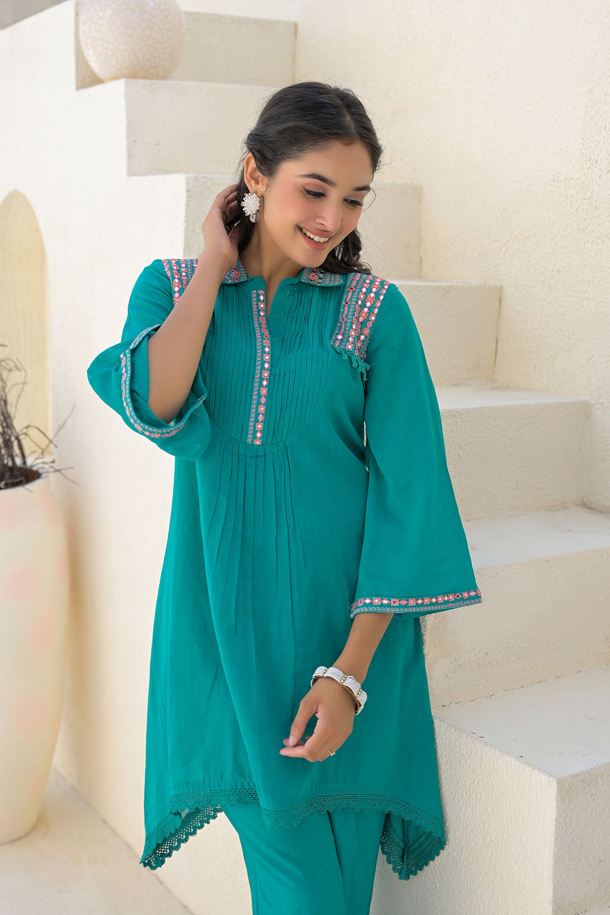 Woman in a teal traditional outfit standing on a staircase.