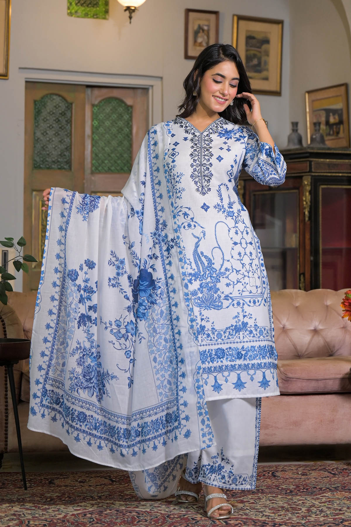 Woman in a blue and white patterned outfit standing in a room with decor elements.