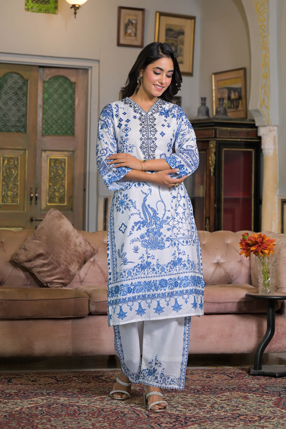 Woman in a blue and white traditional outfit standing in a living room.