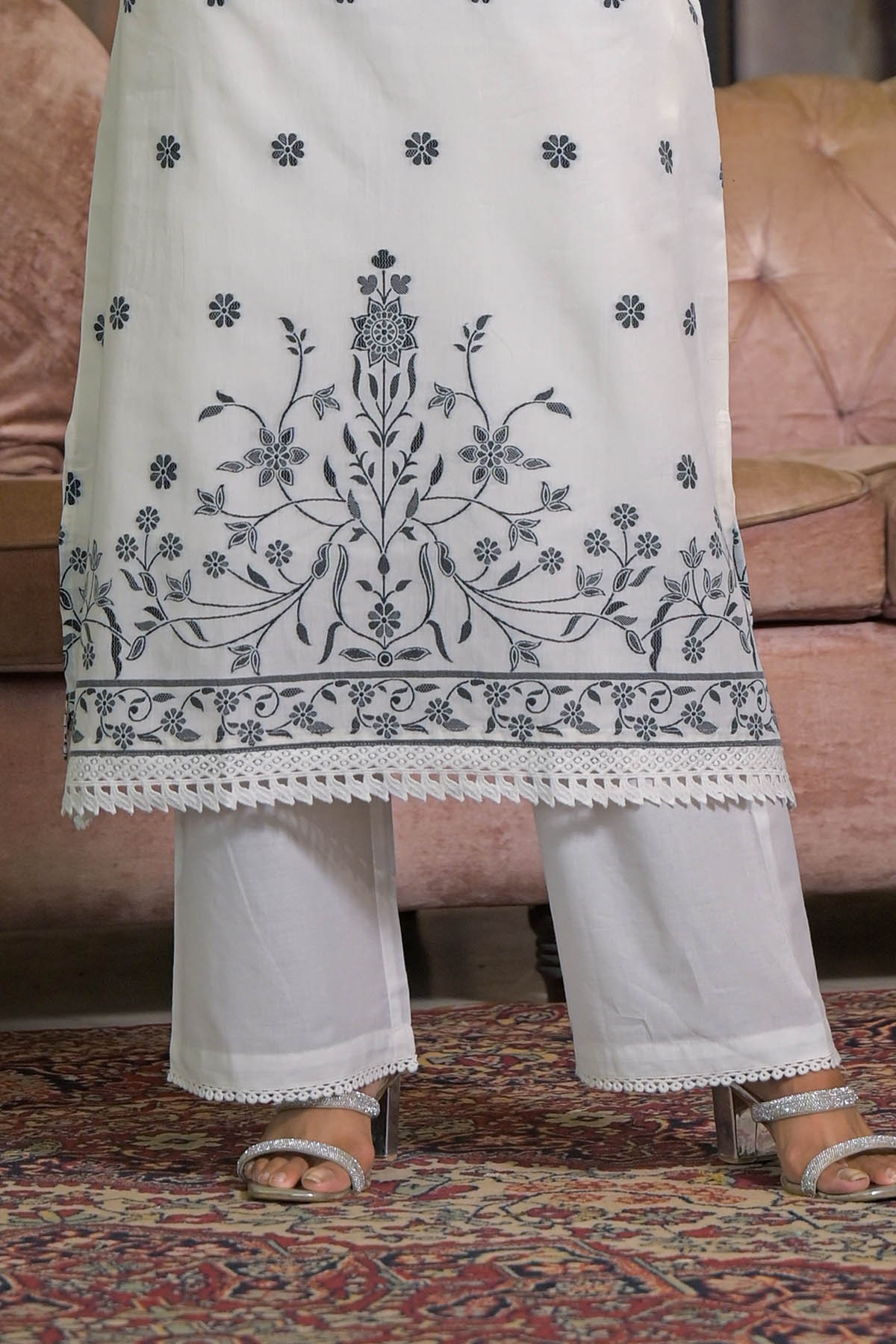 White embroidered kurta with matching pants on a patterned rug.