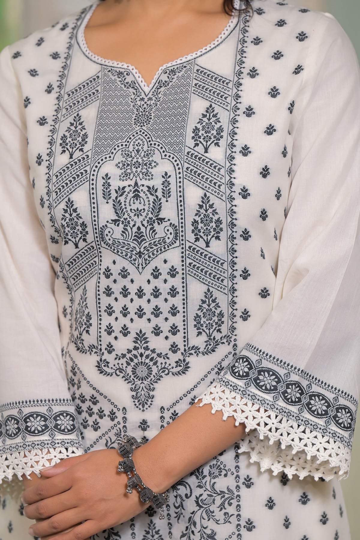 White kurta with black intricate embroidery on a person wearing it.