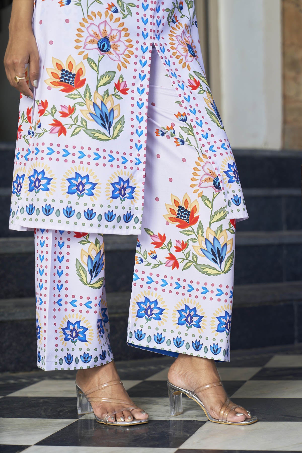 Person wearing a colorful floral outfit on a checkered floor.