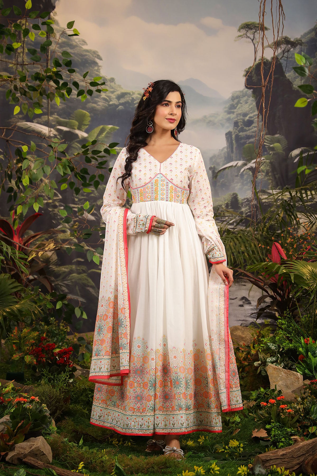Woman in a traditional outfit standing in a lush, forested landscape