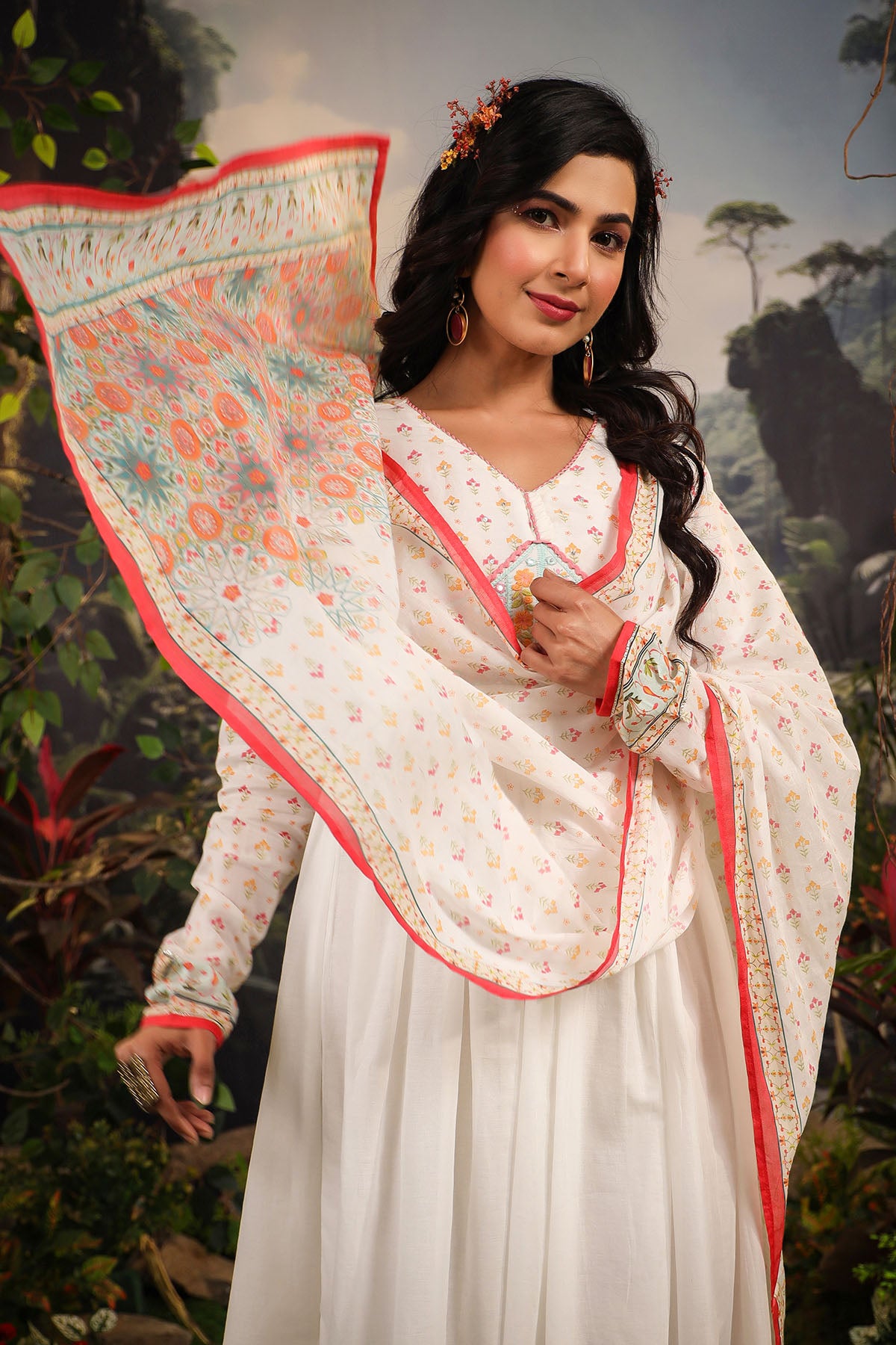 Woman in a traditional outfit with a floral dupatta against a natural background