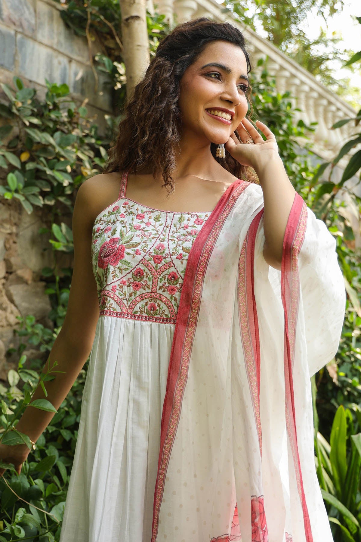 Woman in a traditional outfit with floral patterns standing outdoors.