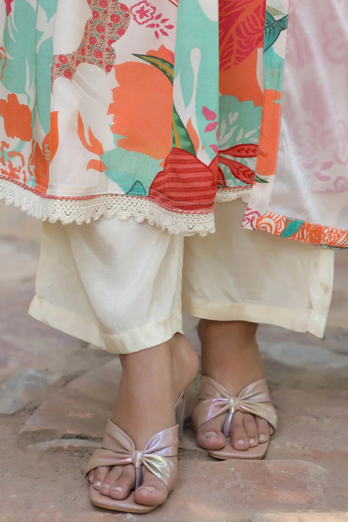 Colorful traditional outfit with floral patterns and a sandal on a textured floor.