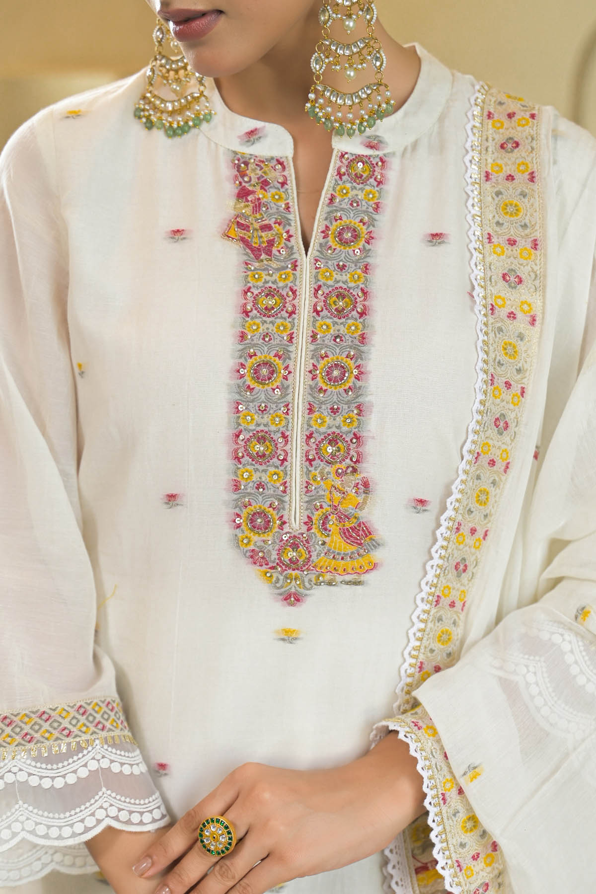 White embroidered traditional outfit with colorful details on a neutral background