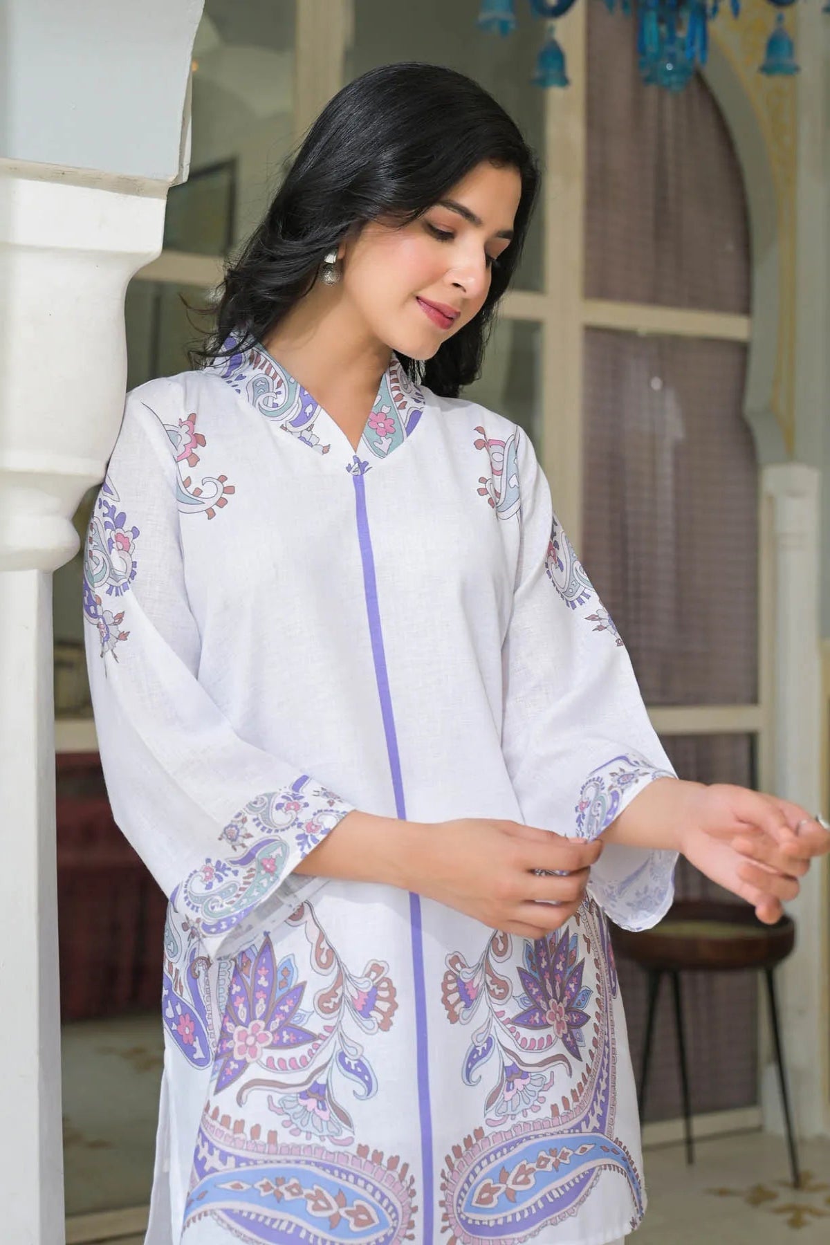 Woman wearing a white embroidered traditional outfit in an indoor setting.