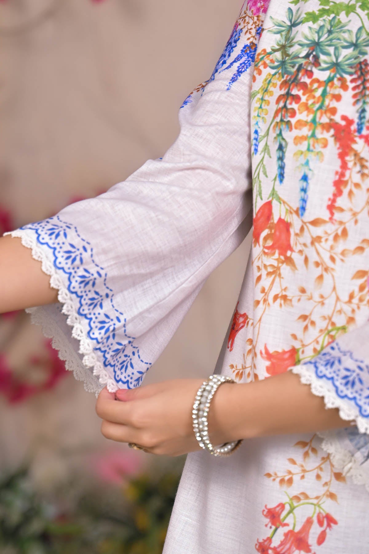 Close-up of a person wearing a colorful floral dress with white lace trim.