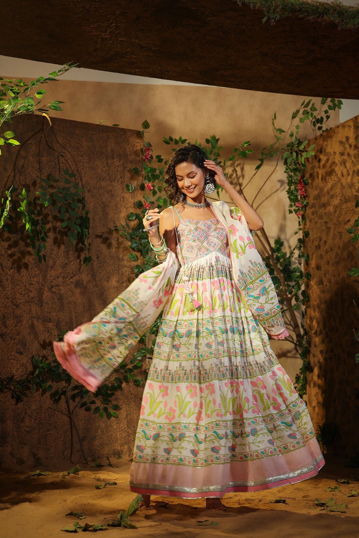 Woman in a floral dress with a scarf, standing in a rustic setting with plants.