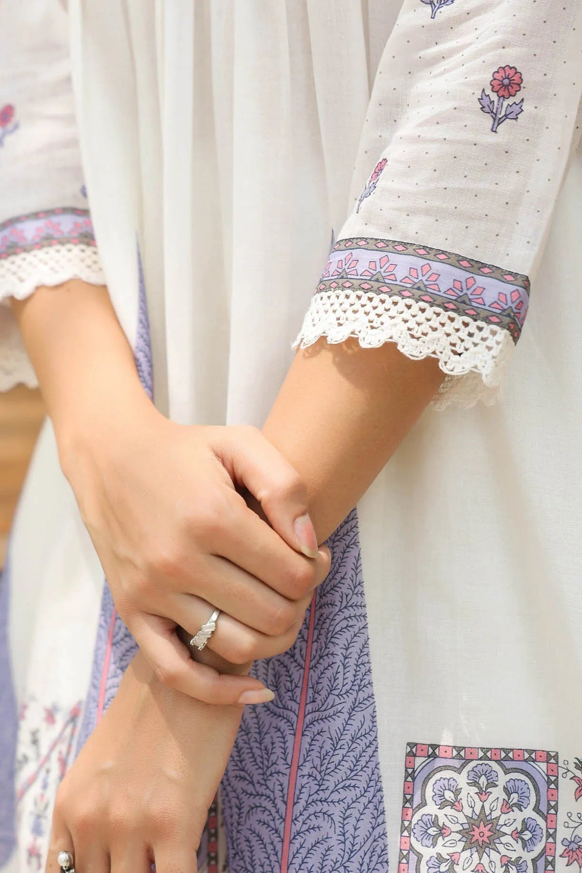 Close-up of a person wearing a white garment with floral embroidery and lace details.