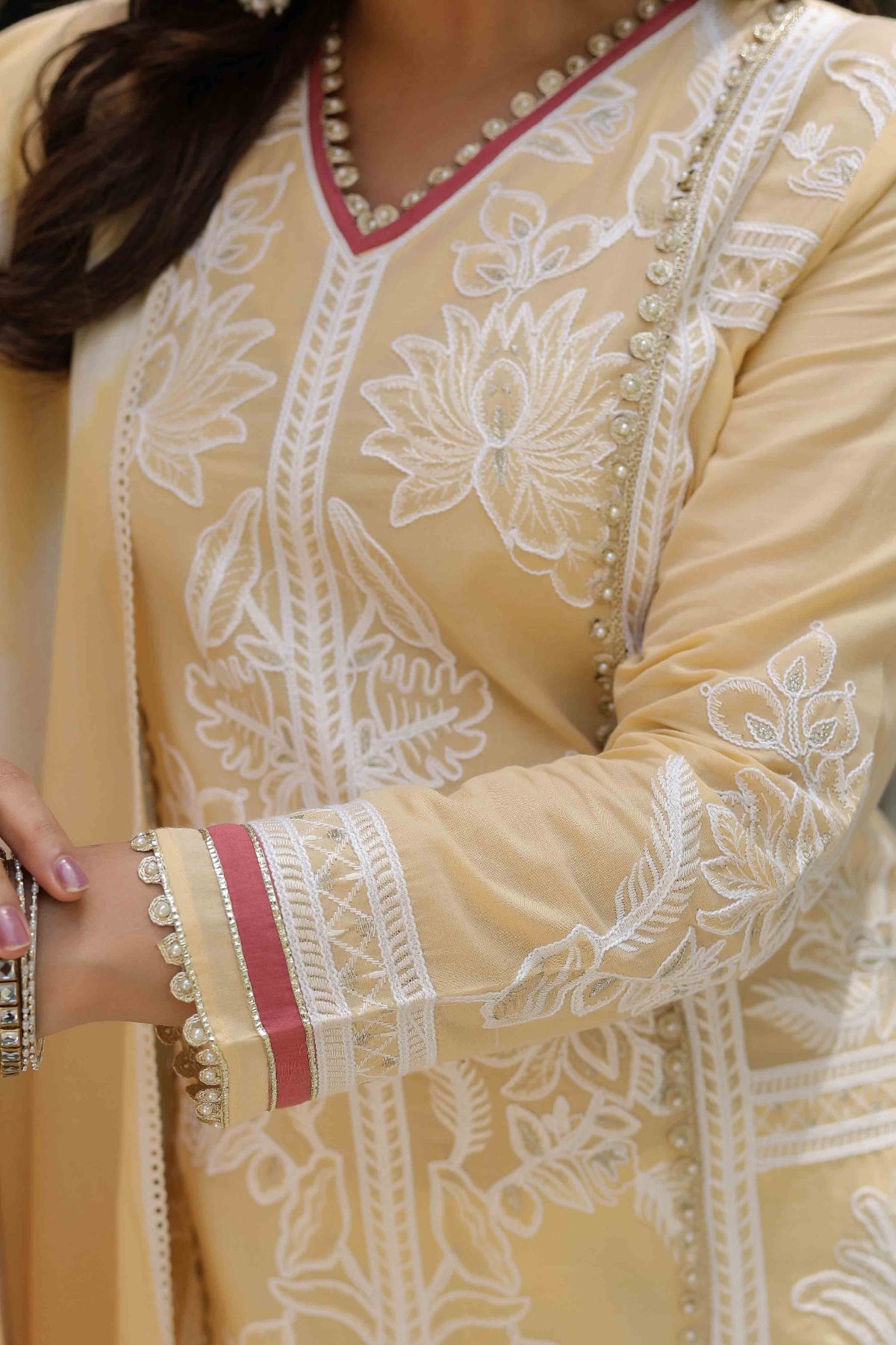 Close-up of a beige embroidered traditional outfit with white patterns