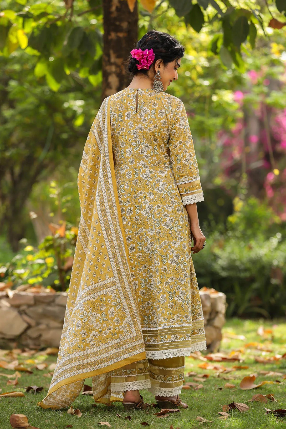 Woman in a yellow floral outfit standing in a garden